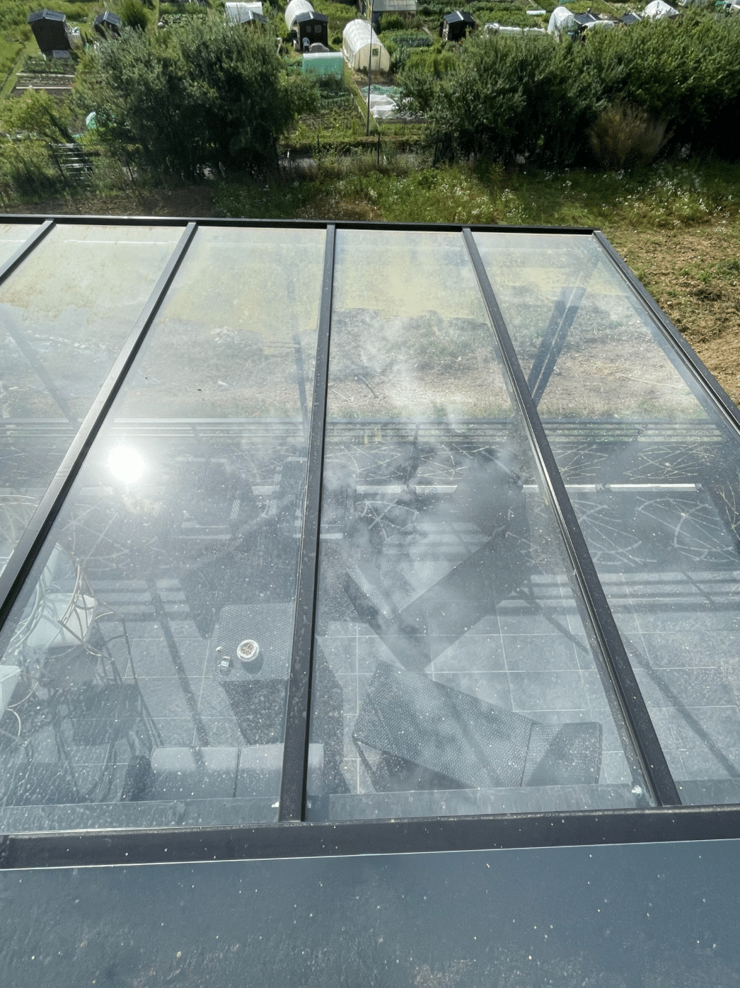 Toit en verre sale avec vue sur un jardin en contrebas.