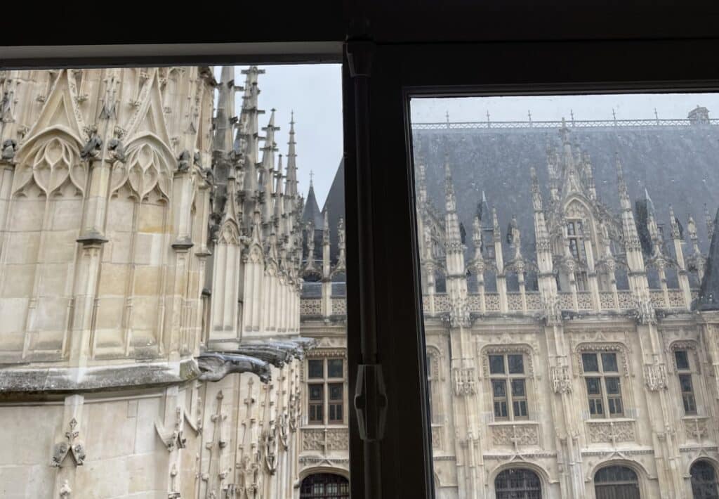 Vue de l'architecture gothique depuis une fenêtre avec des détails ornementaux.